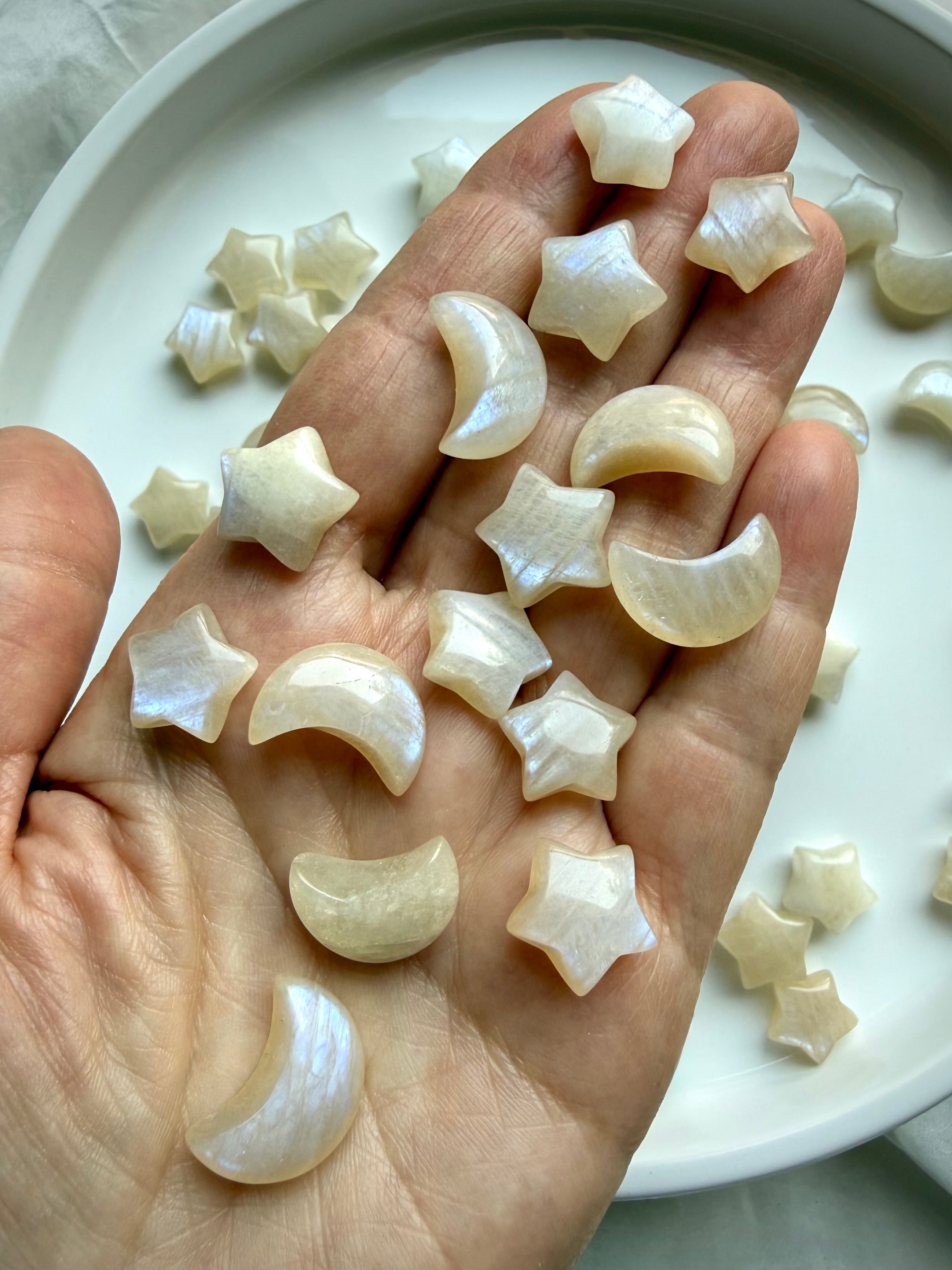 Moonstone moon and star crystal carvings displayed in hand showing size and flash