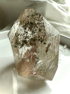 A self standing Lodolite Garden Quartz Crystal shown on a white plate photographed in natural light