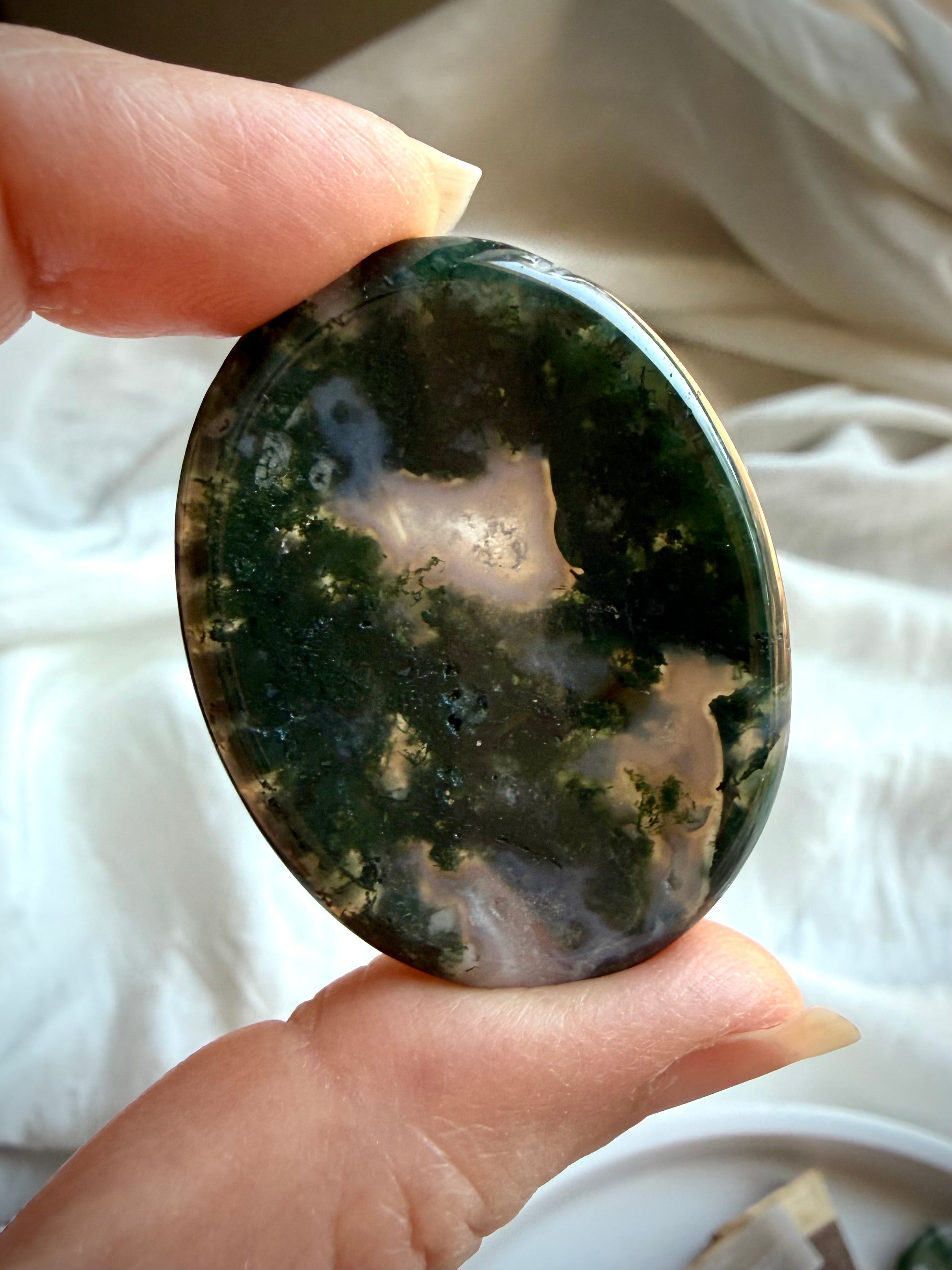 Moss Agate oval thumb stone held in hand with rich moss inclusions and translucent quartz