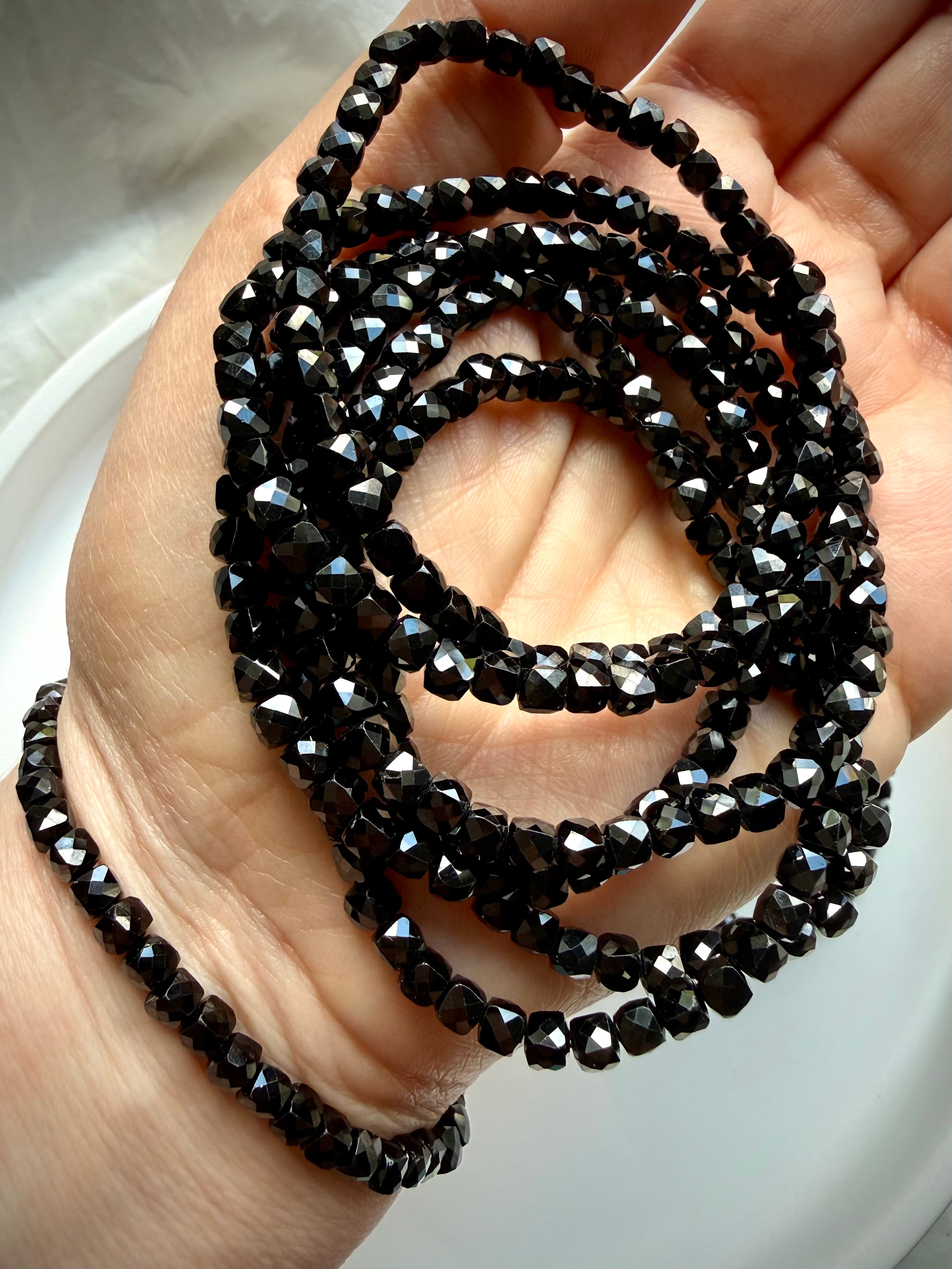 stacked black spinel bracelets on hand for grounding protection and everyday wear