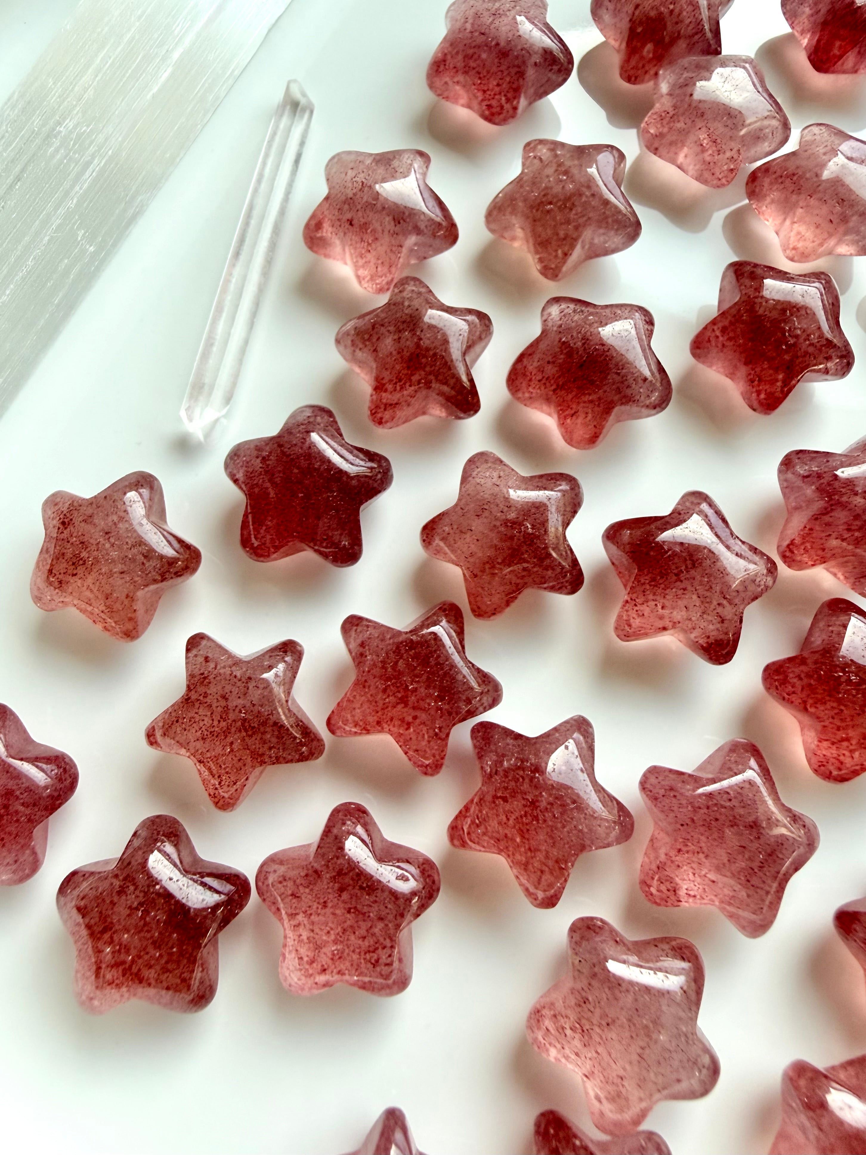 Strawberry Quartz mini crystal stars on white highlighting variations in shape, sparkle & red colors