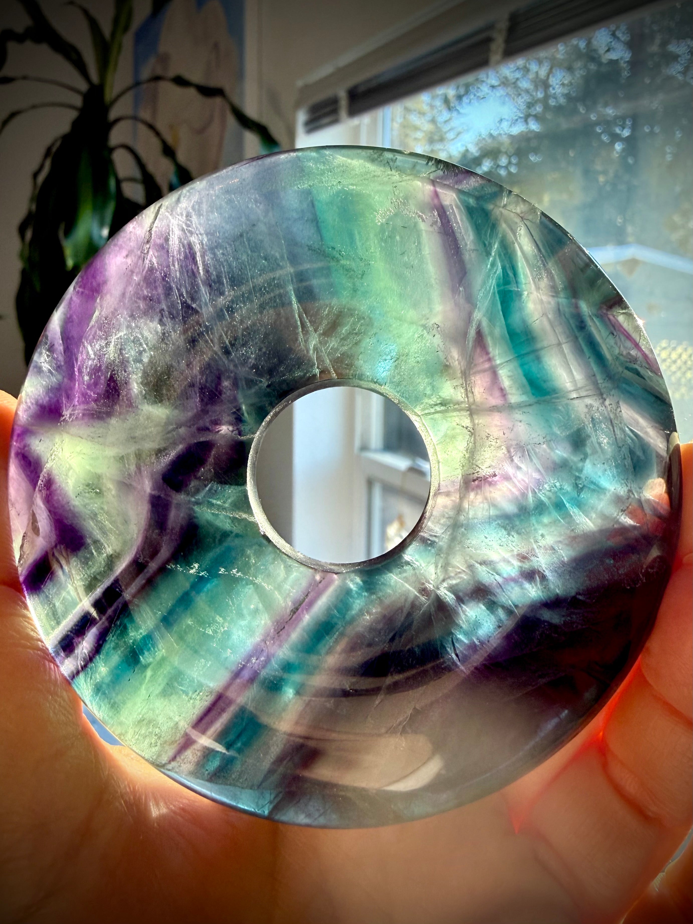 Polished rainbow fluorite donut crystal with translucent layers and color zoning