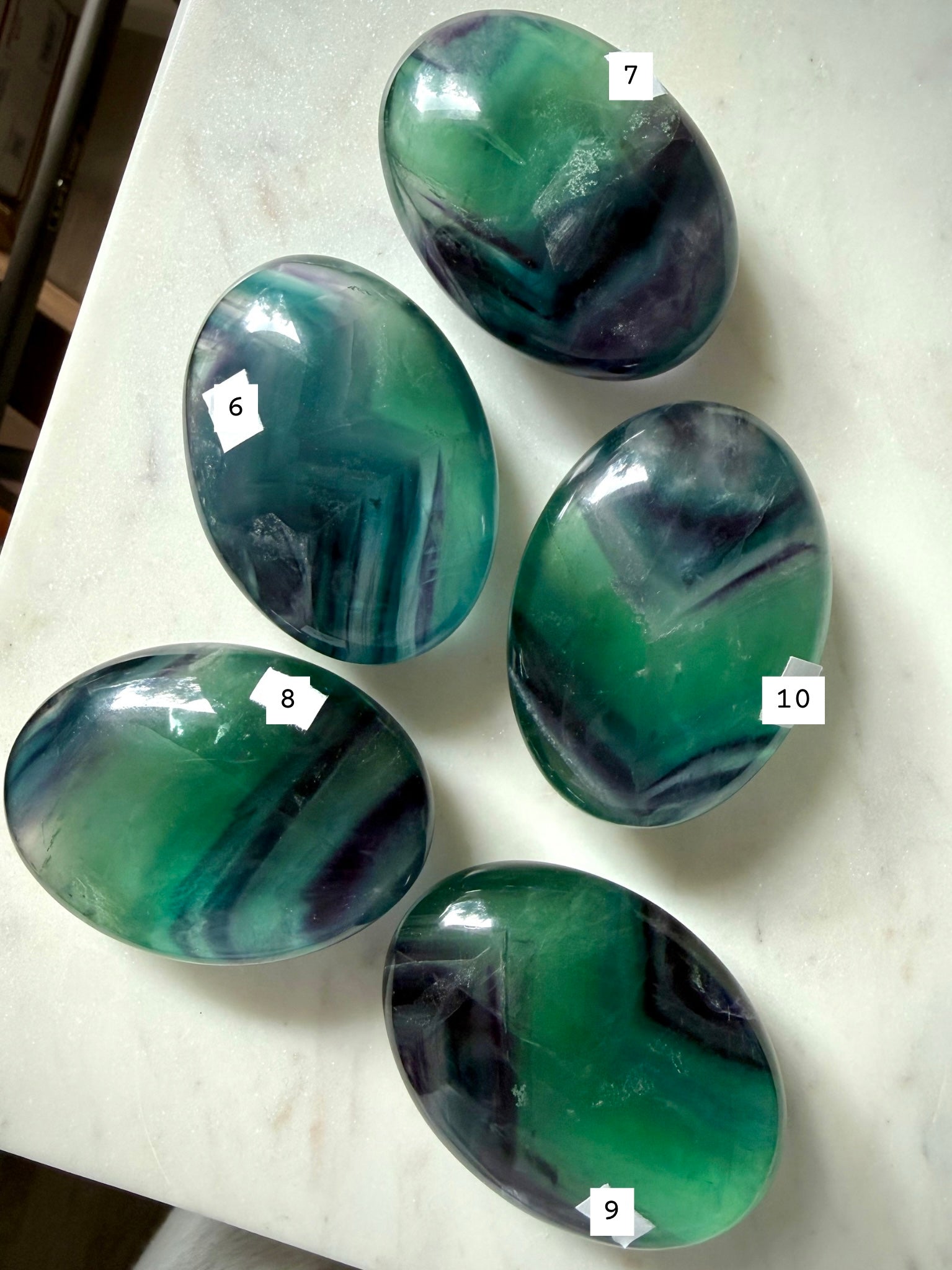 Large teal fluorite palm stones labeled 6–10, displaying saturated blue green banding and natural internal movement