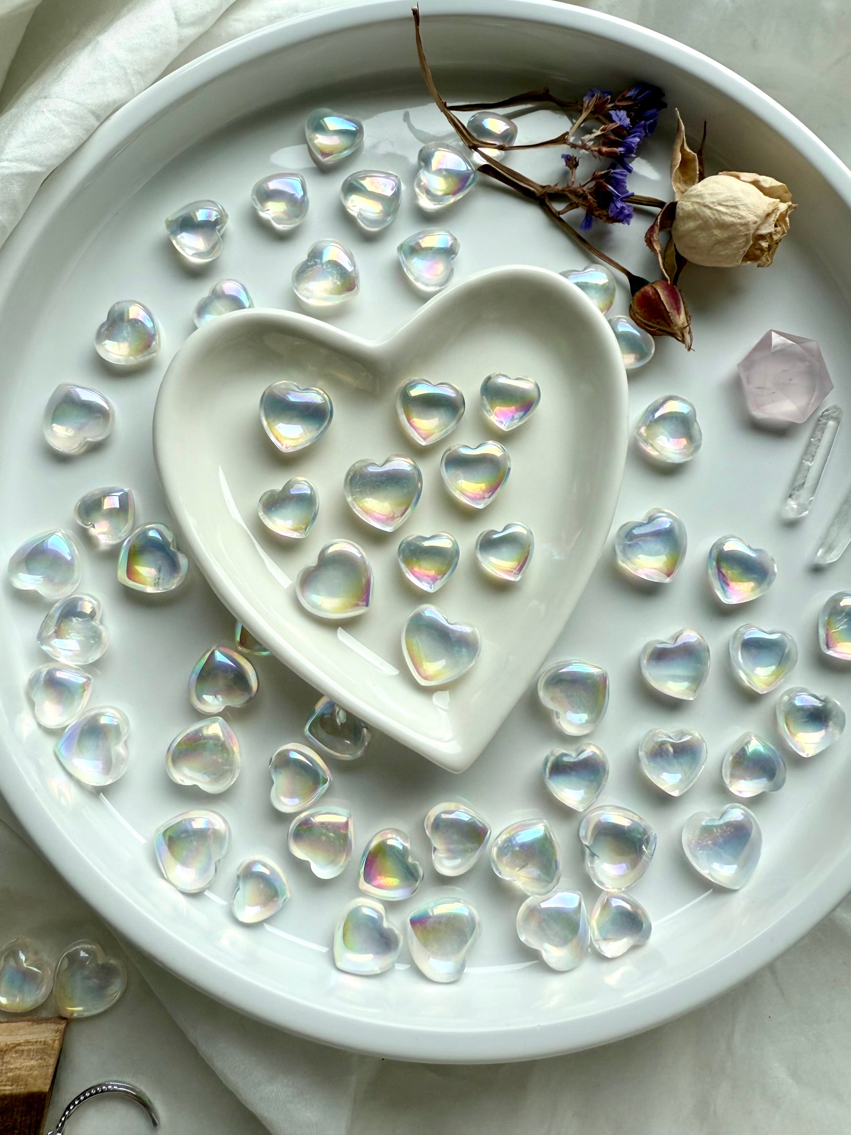 Aura quartz hearts with rose, statice, Lemurian points, and pink faceted gem in a heart bowl altar setup