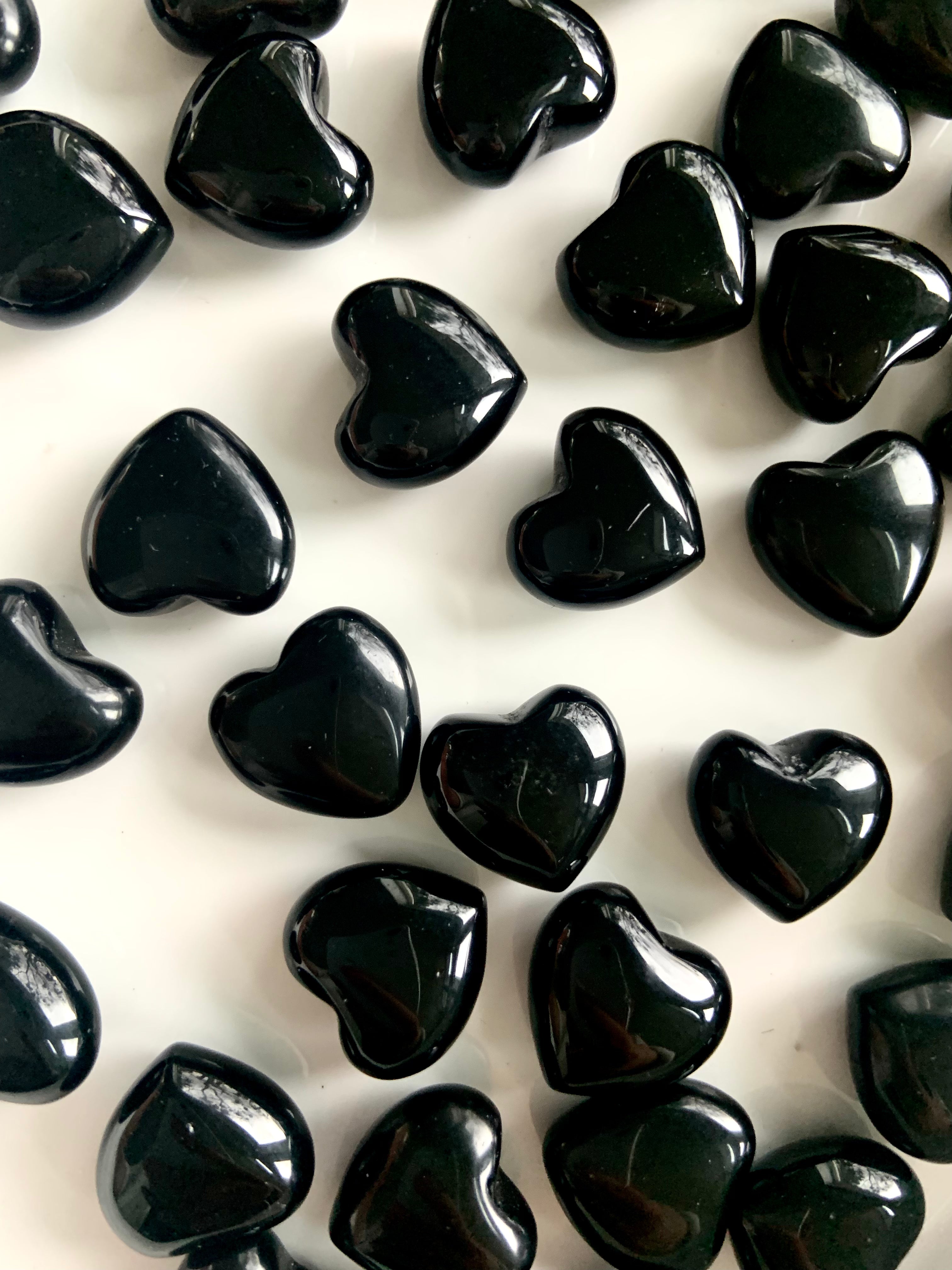 Close up view of our mini sized Black Obsidian Hearts shown on a white plate