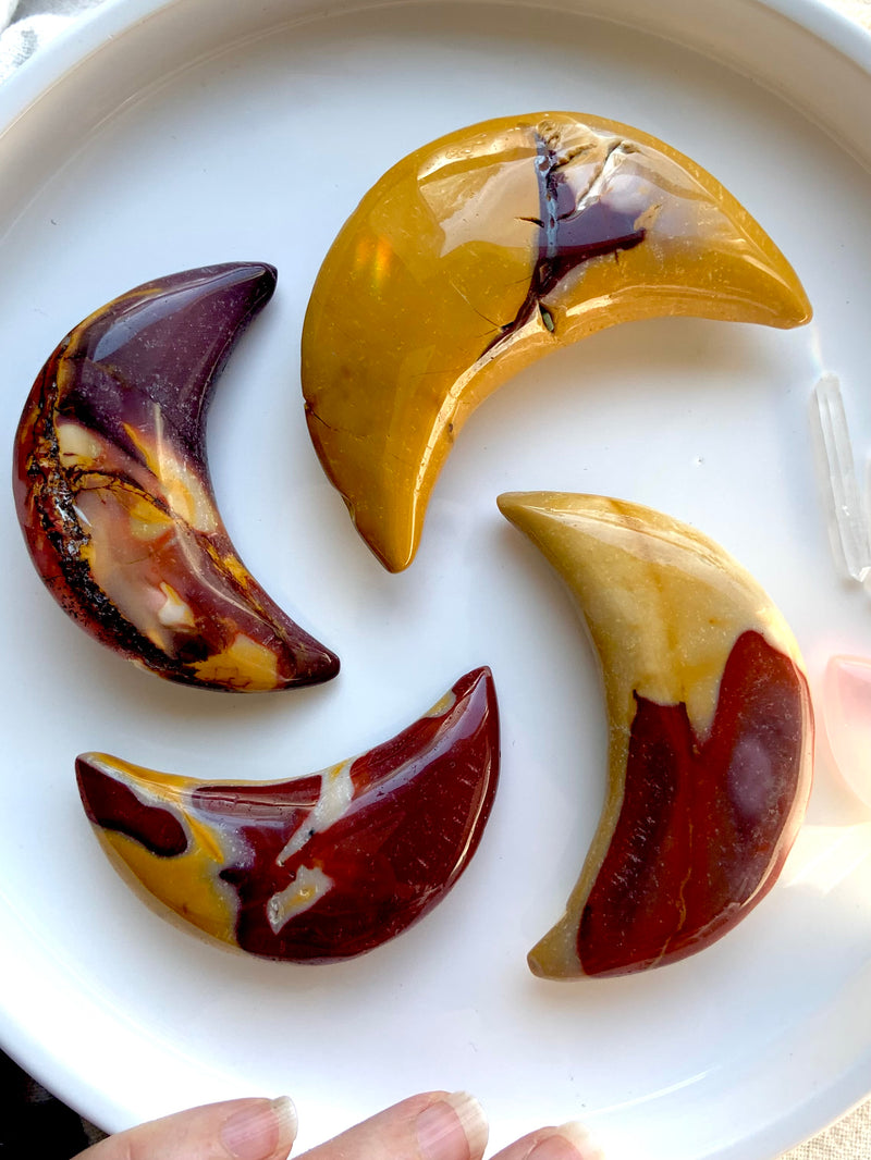 Big, colorful Mookaite Jasper Crescent Moon Carvings shown on a white plate. Choose your favorite from the dropdown menu.