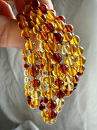 Hand holding strands of glowing amber bracelets in honey, cognac, and golden hues – Solar Plexus crystal for vitality and light