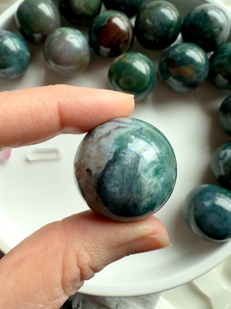 Colorful moss agate mini spheres shown held between my fingers for scale