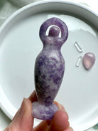 Our purple Lepidolite Standing Goddess Statue shown on a white plate
