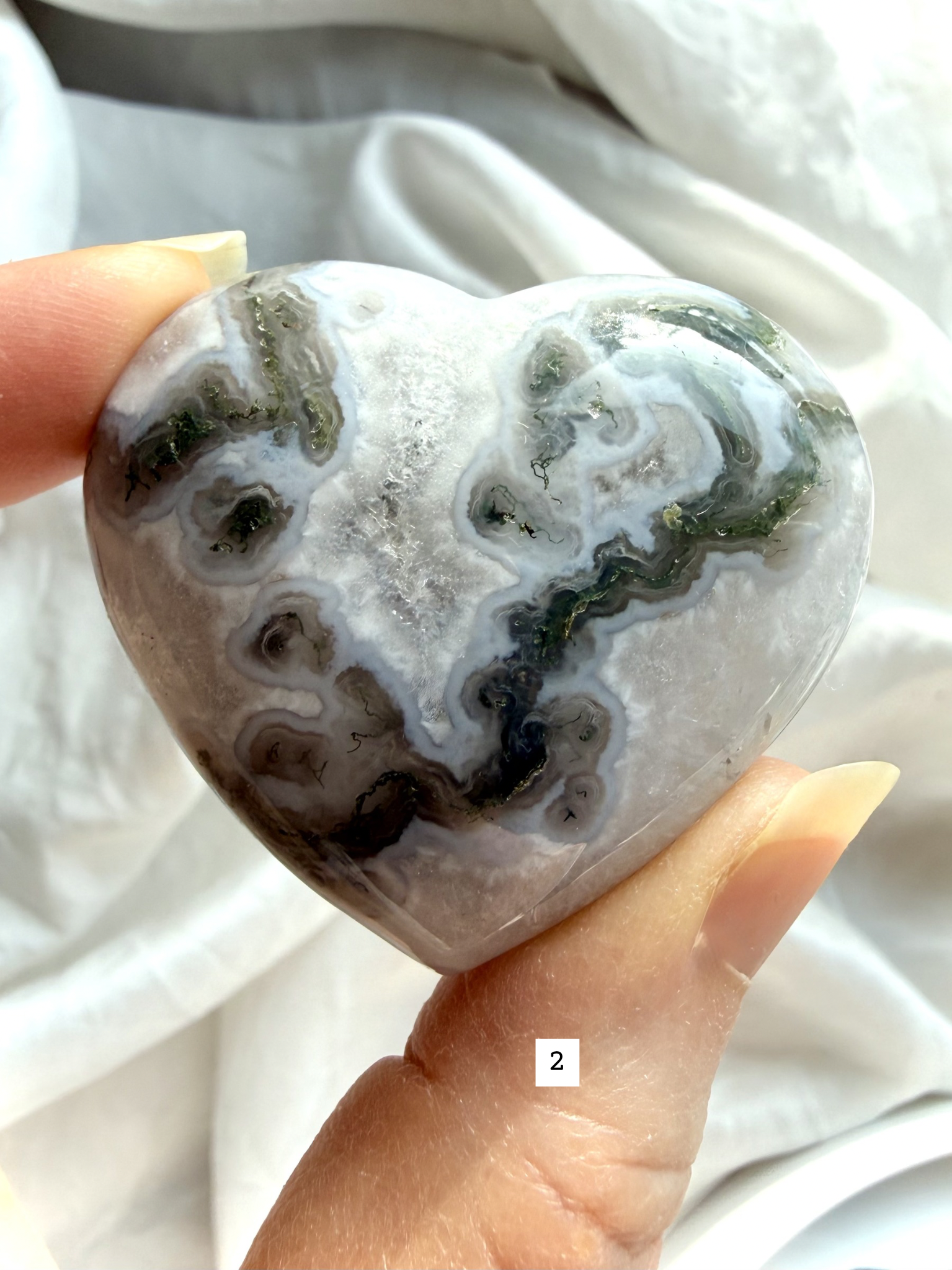 moss agate heart carving option 2 in hand showing quartz inclusions and earthy green mineral inclusions