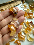 Closeup of Golden Healer Quartz crescent moons on hand showing natural golden color variations and polished crystal details