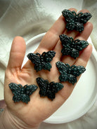 Multiple Wuji jade butterfly crystal carvings held in hand showing natural Guatemalan jade