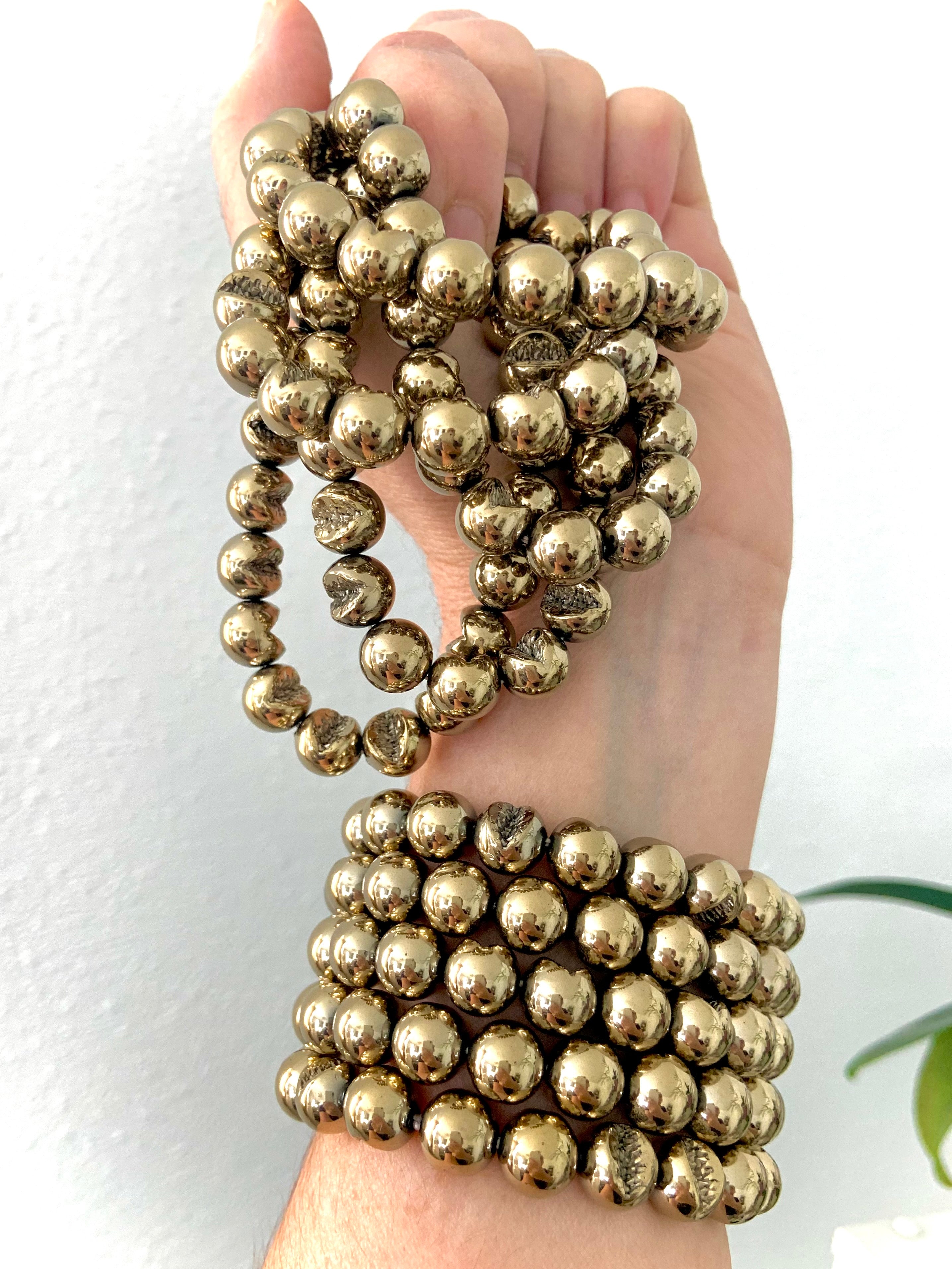 Wrist adorned with stacked Pyrite bracelets — crystal jewelry for abundance, protection & manifestation