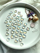 Overhead view of Aura quartz heart carving grid with dried flowers, pink faceted gem, and Lemurian crystals