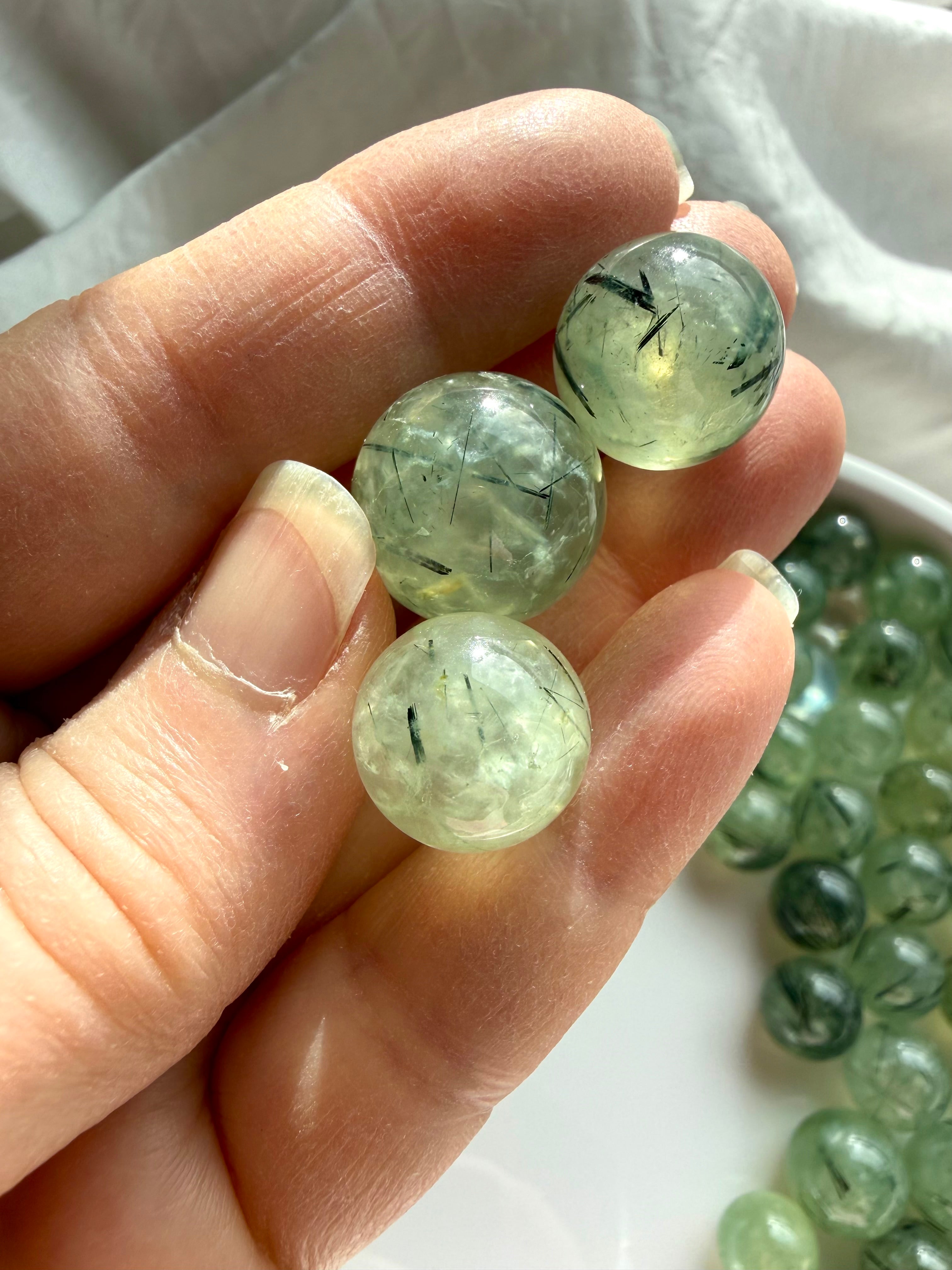 prehnite mini spheres in hand showing size scale and natural epidote inclusions
