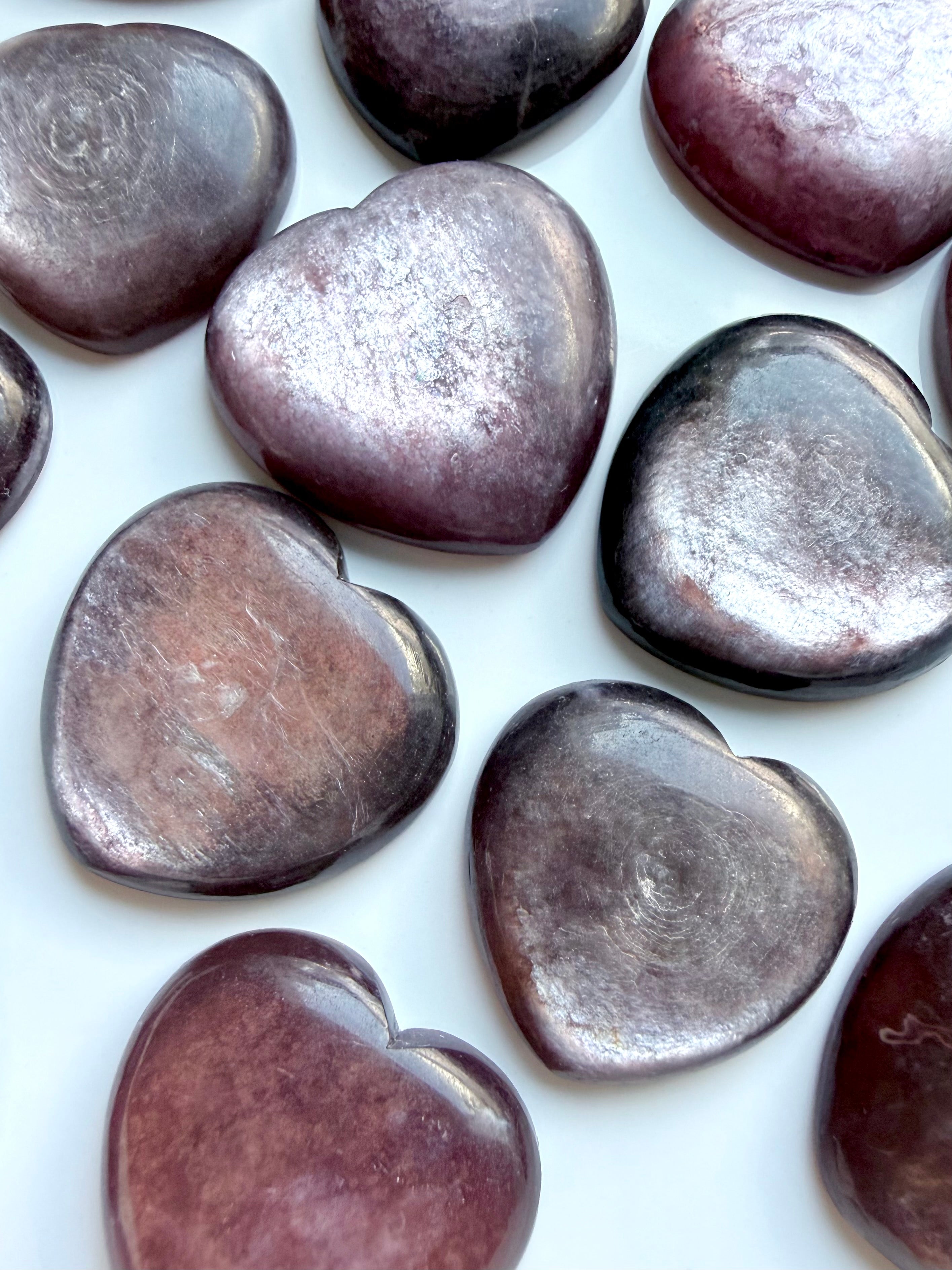 Gem Lepidolite heart carvings close-up with silvery mica flash and lavender plum hues