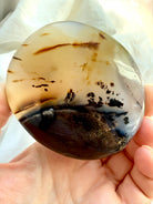 Dendritic Agate freeform held in hand, revealing delicate black dendritic formations and warm golden honey-colored layers