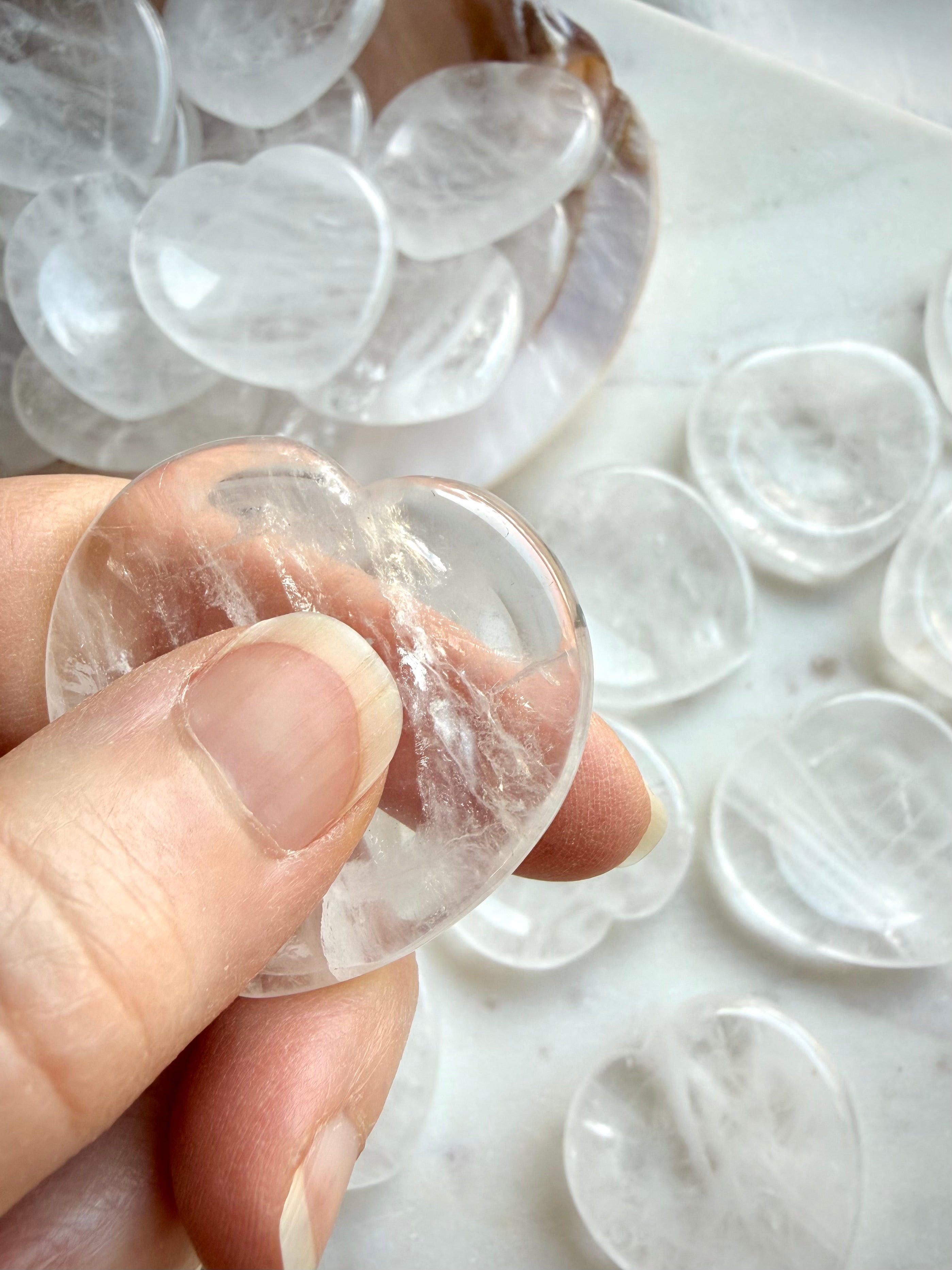 clear quartz heart worry stones in hand showing smooth polished thumb stone shape for calming energy