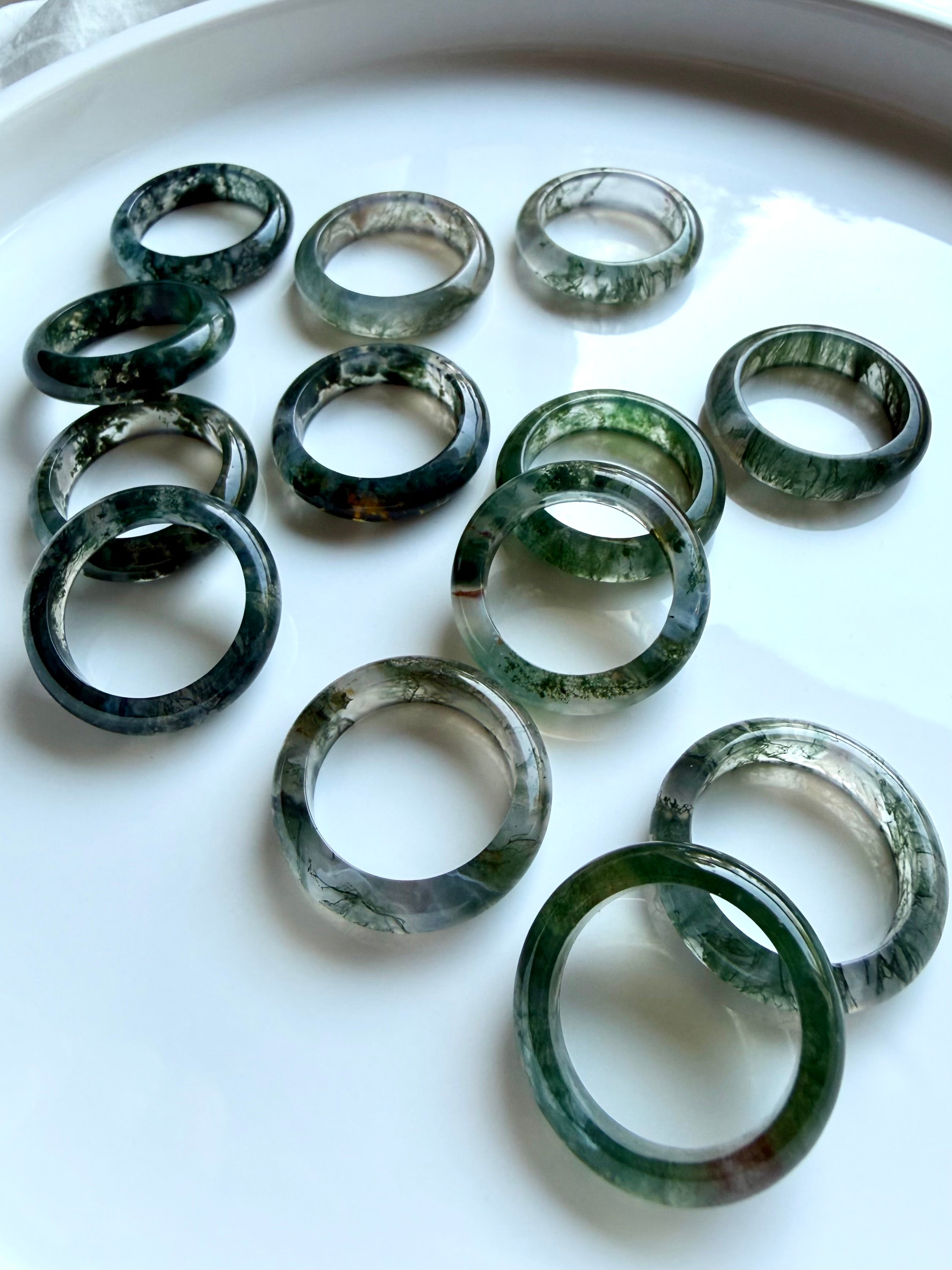 moss agate rings arranged on white with organic green inclusions, crystal band rings for heart chakra and stability