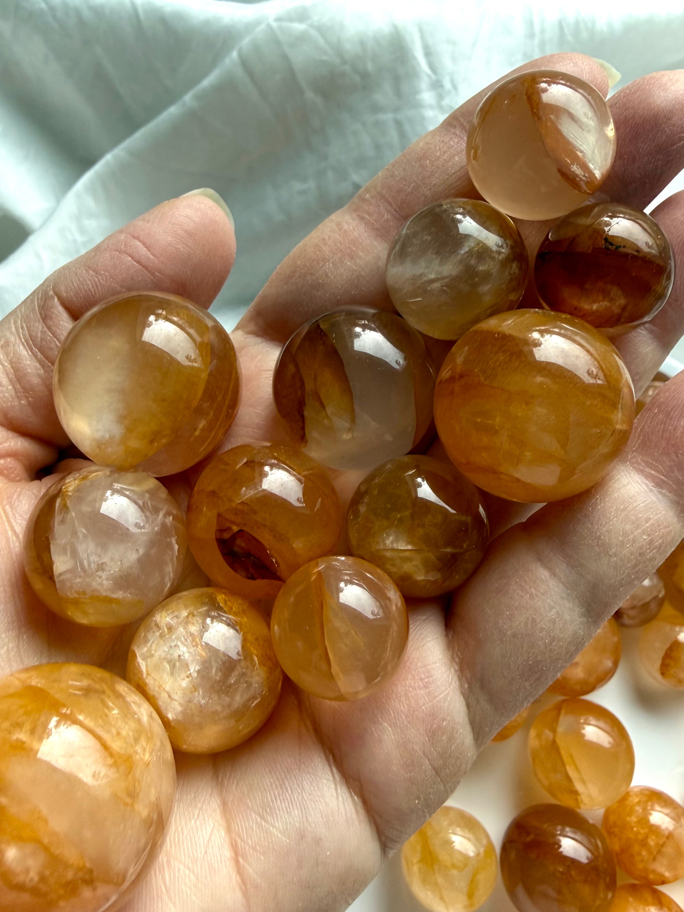 Close up of golden healer quartz mini spheres held in hand showing size scale and natural inclusions