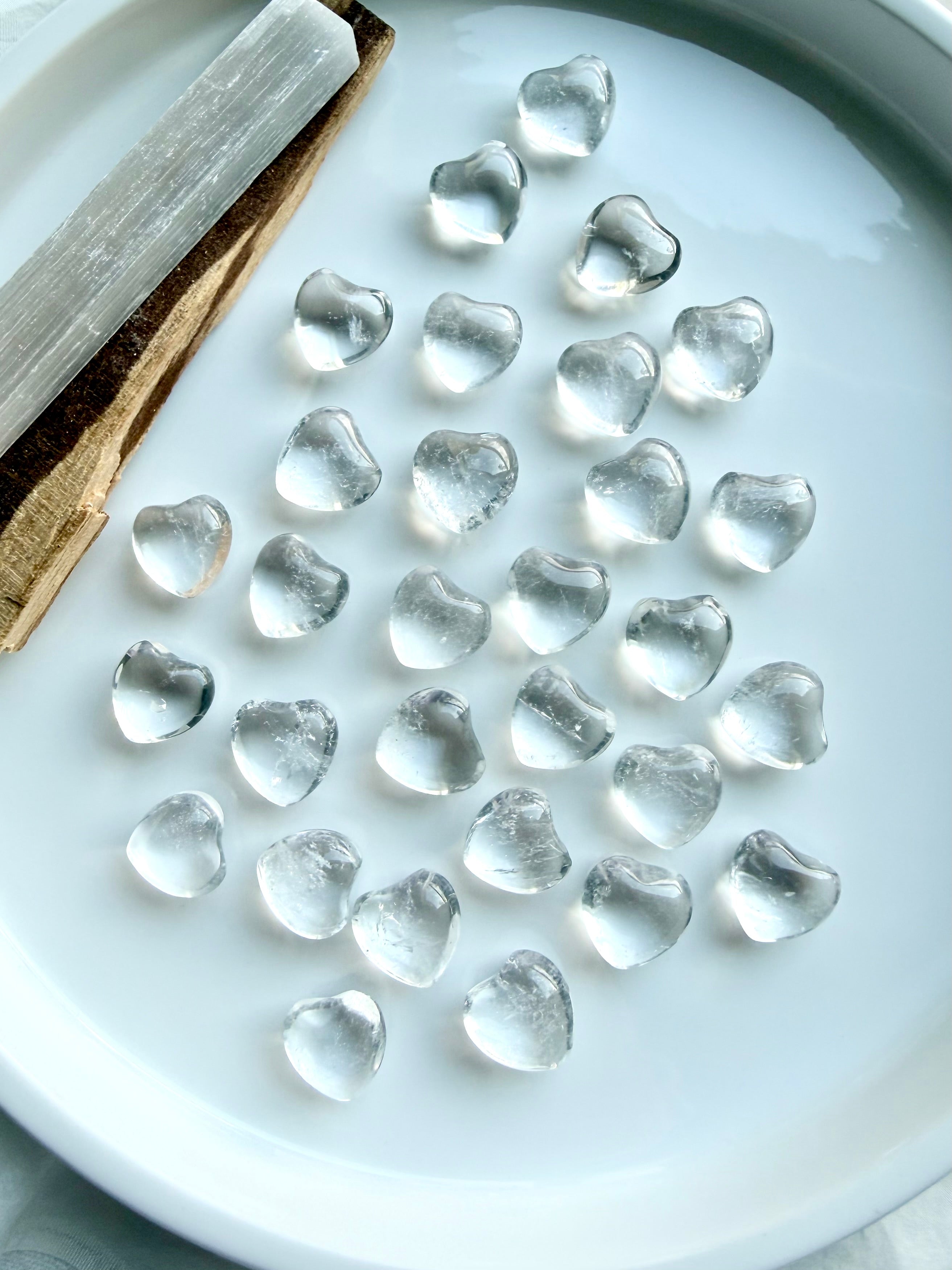 Mini Clear Quartz crystal hearts with high clarity and natural quartz inclusions on display tray -- more alts: 