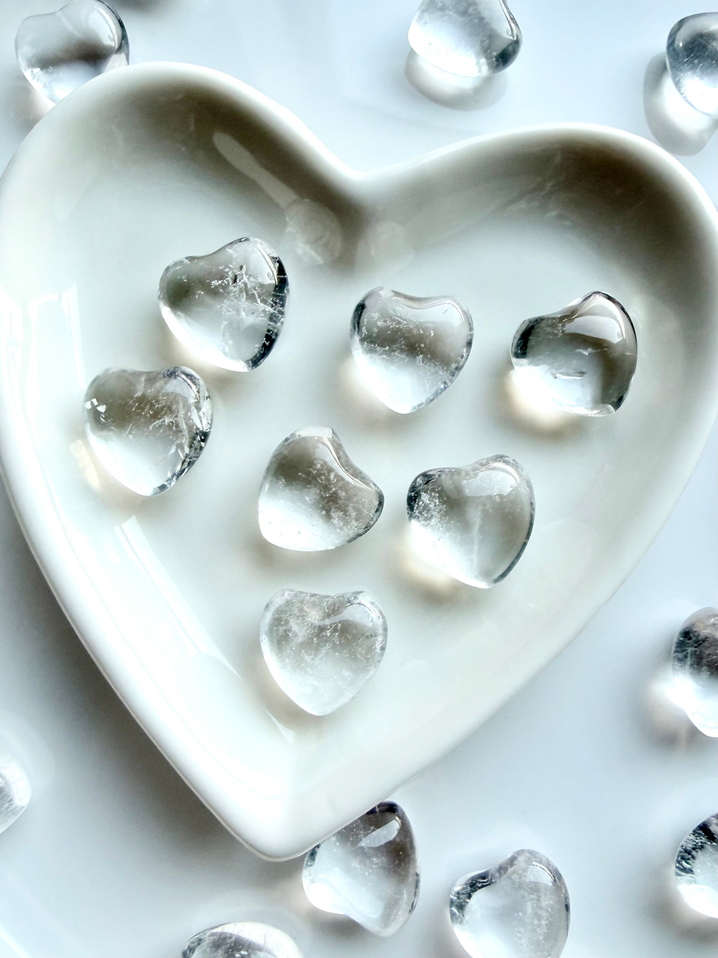 Close up of mini Clear Quartz hearts in white heart shaped bowl showing transparent quartz crystal