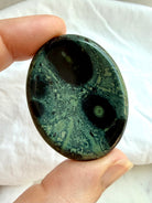 Close-up Kambaba Jasper worry stone showing forest and sage green color, black markings, and intricate orbicular patterns