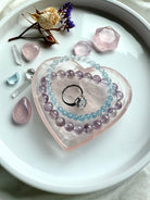 Rose Quartz heart bowl styled as a vanity jewelry dish with bracelets and ring, a giftable piece of metaphysical décor for love and healing.