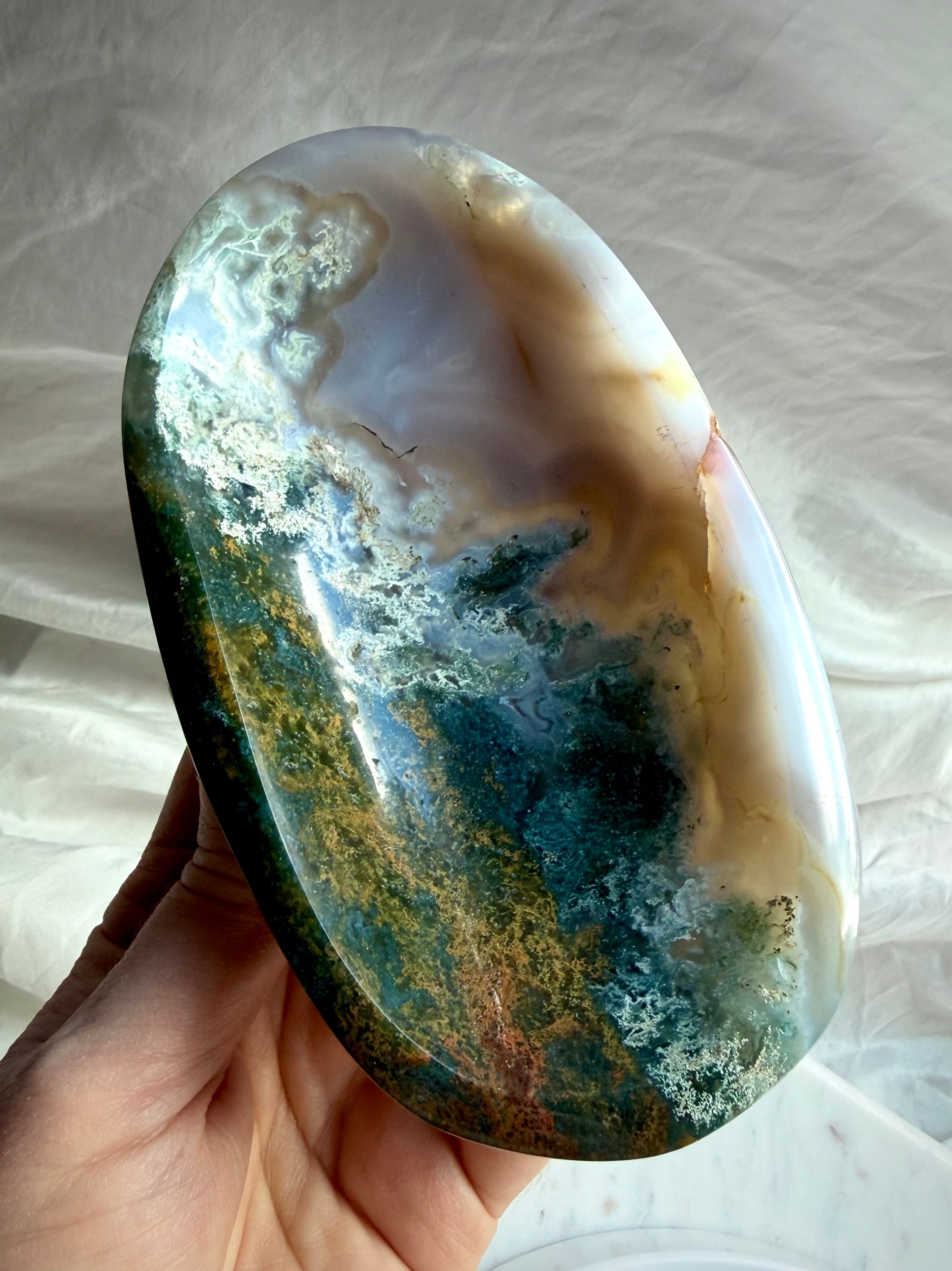 Moss Agate crystal bowl held in hand showing deep green inclusions, translucent agate and natural landscape-like formations