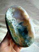 Moss Agate crystal bowl held in hand showing deep green inclusions, translucent agate and natural landscape-like formations