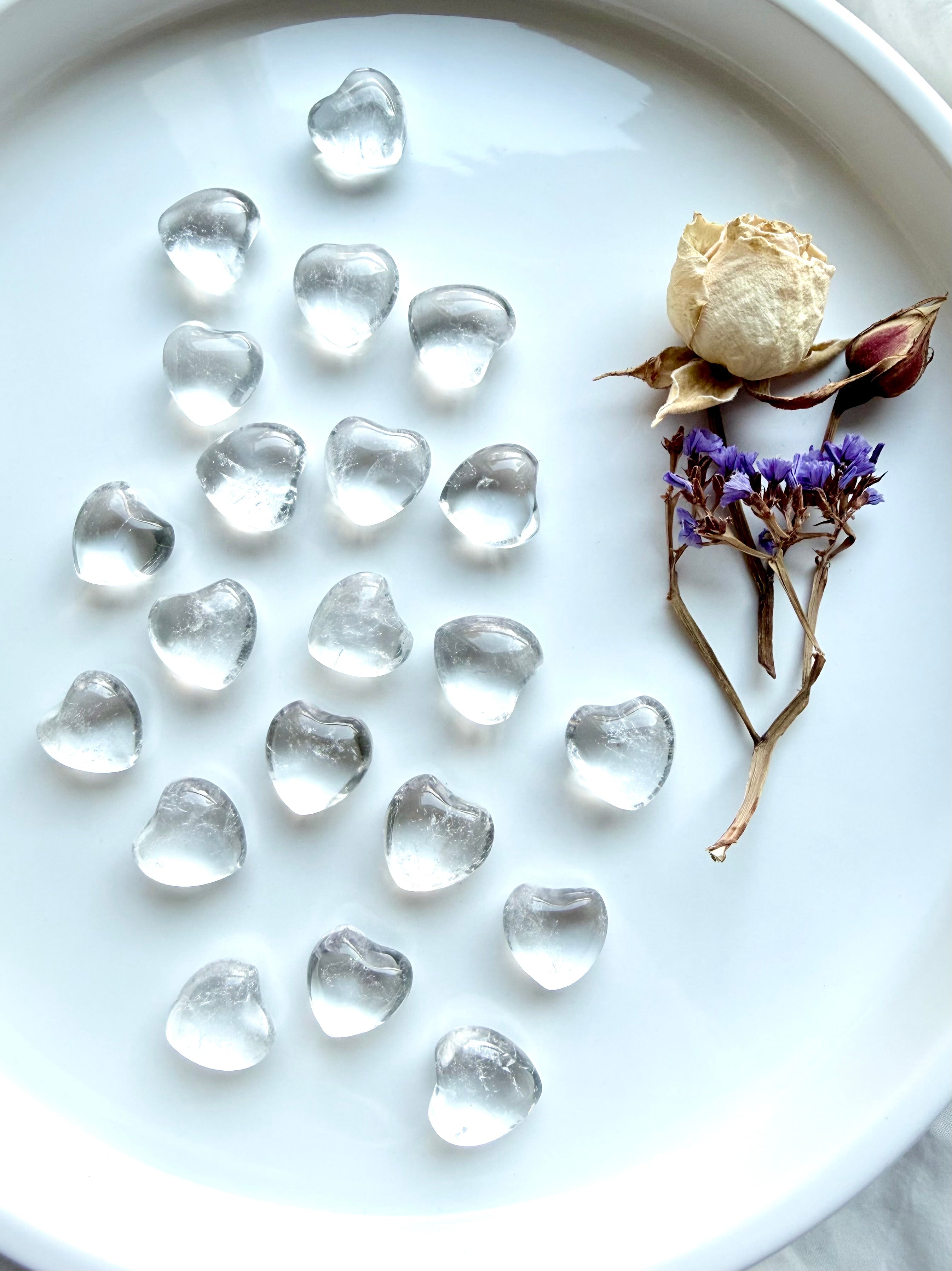 Mini Clear Quartz hearts arranged on white tray with dried flowers, high clarity quartz crystal hearts