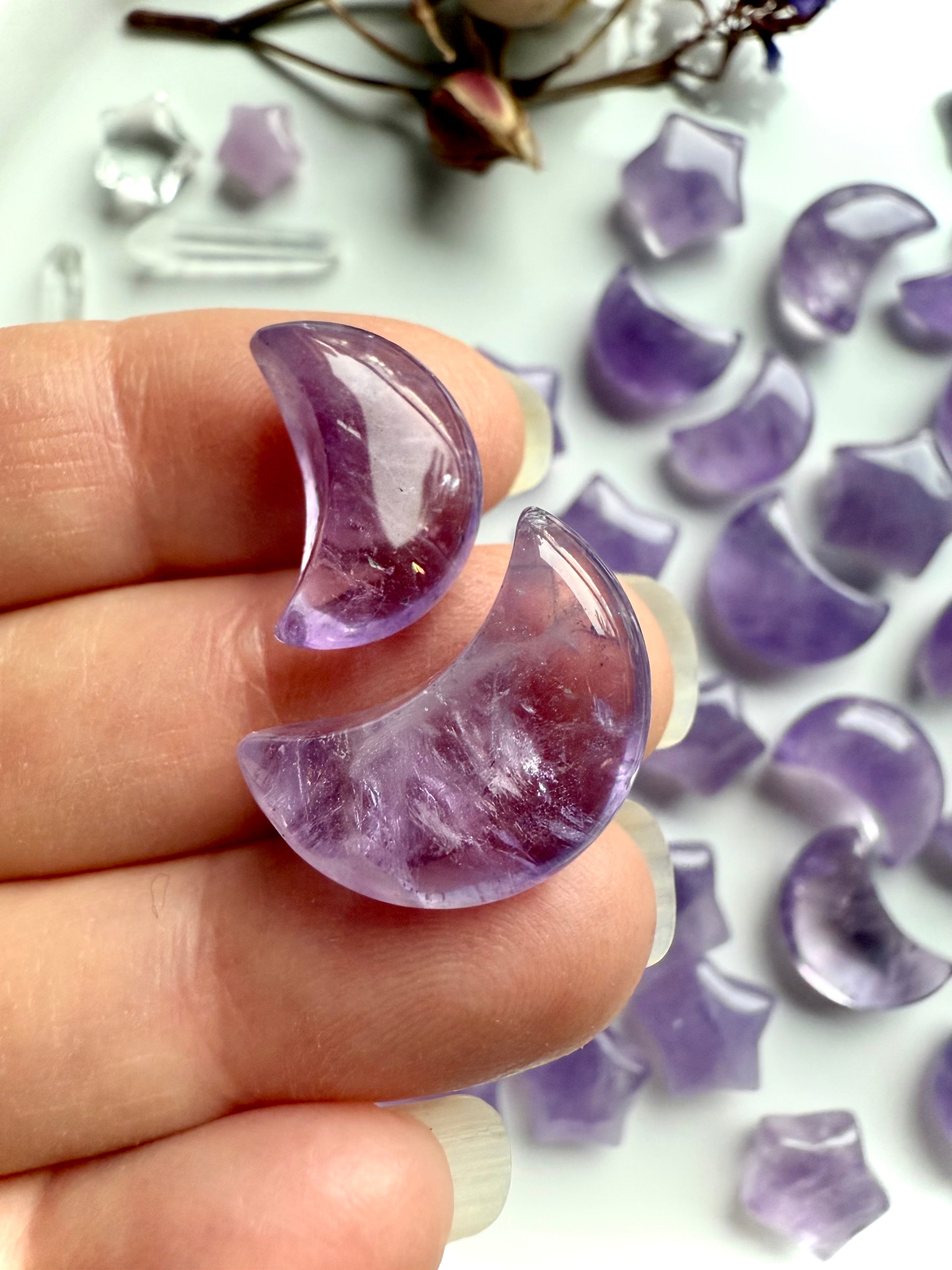Closeup view of a two amethyst moon crystal carvings with translucent purple tones