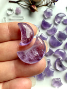 Closeup view of a two amethyst moon crystal carvings with translucent purple tones