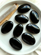 Collection of Black Obsidian palm stones displaying smooth polished surfaces and rich volcanic glass luster