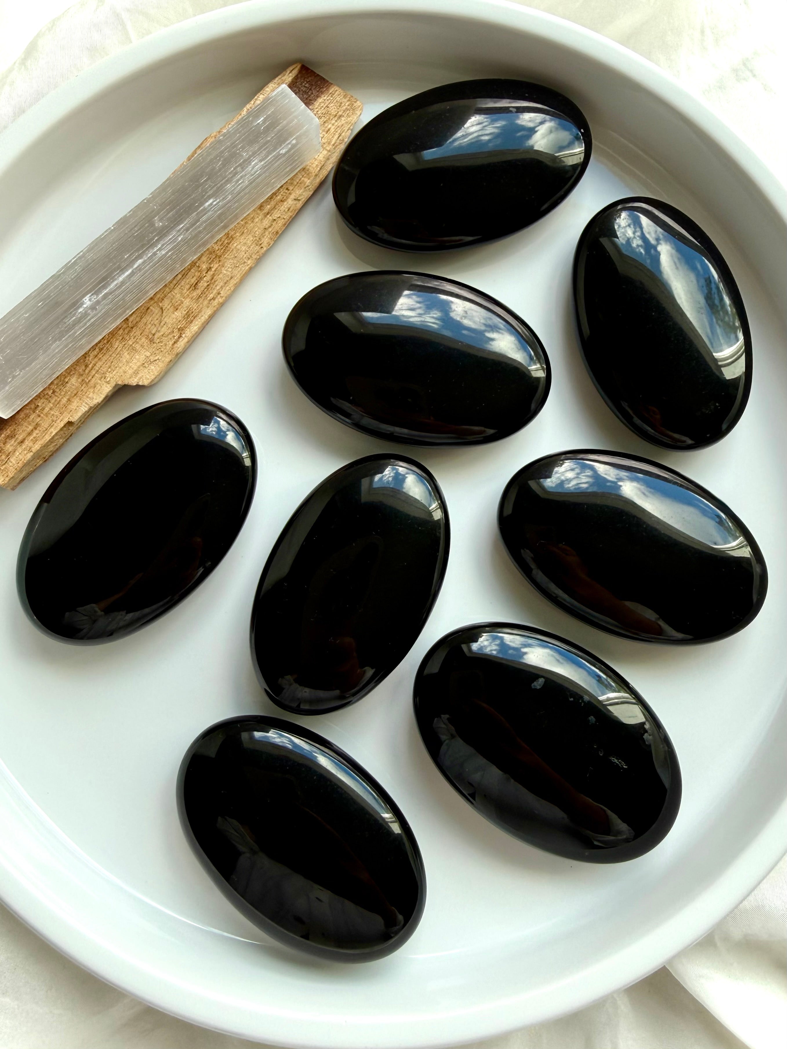Collection of Black Obsidian palm stones displaying smooth polished surfaces and rich volcanic glass luster
