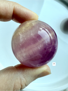 high grade Silky Magenta Fluorite crystal sphere with rich violet and pink color zoning held in hand