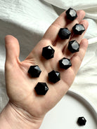 An array of Black Obsidian hexagons resting in an open palm