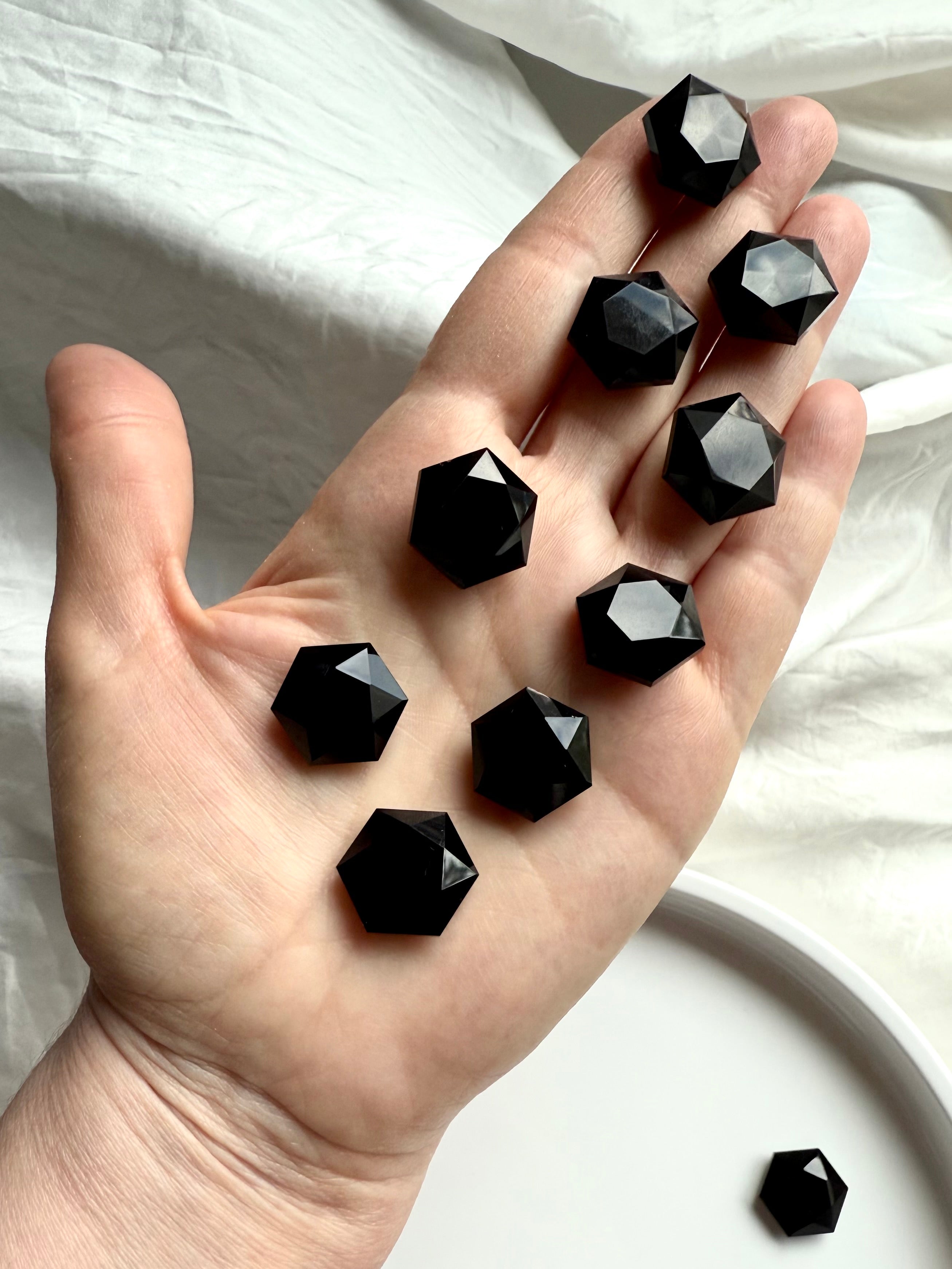 An array of Black Obsidian hexagons resting in an open palm