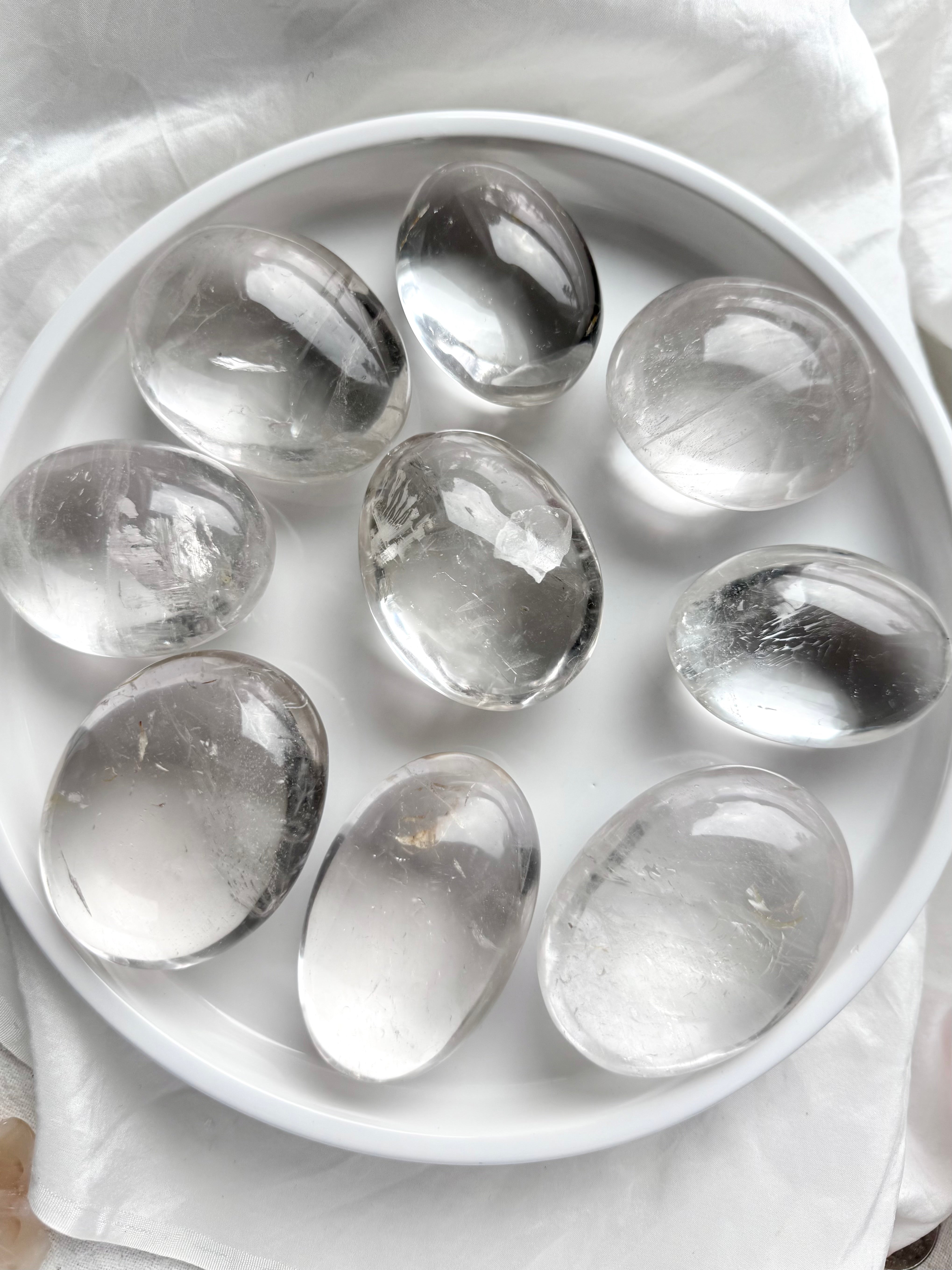 An array of clear quartz meditation stones, smooth polished palm stones for energy work