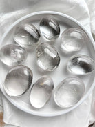 An array of clear quartz meditation stones, smooth polished palm stones for energy work