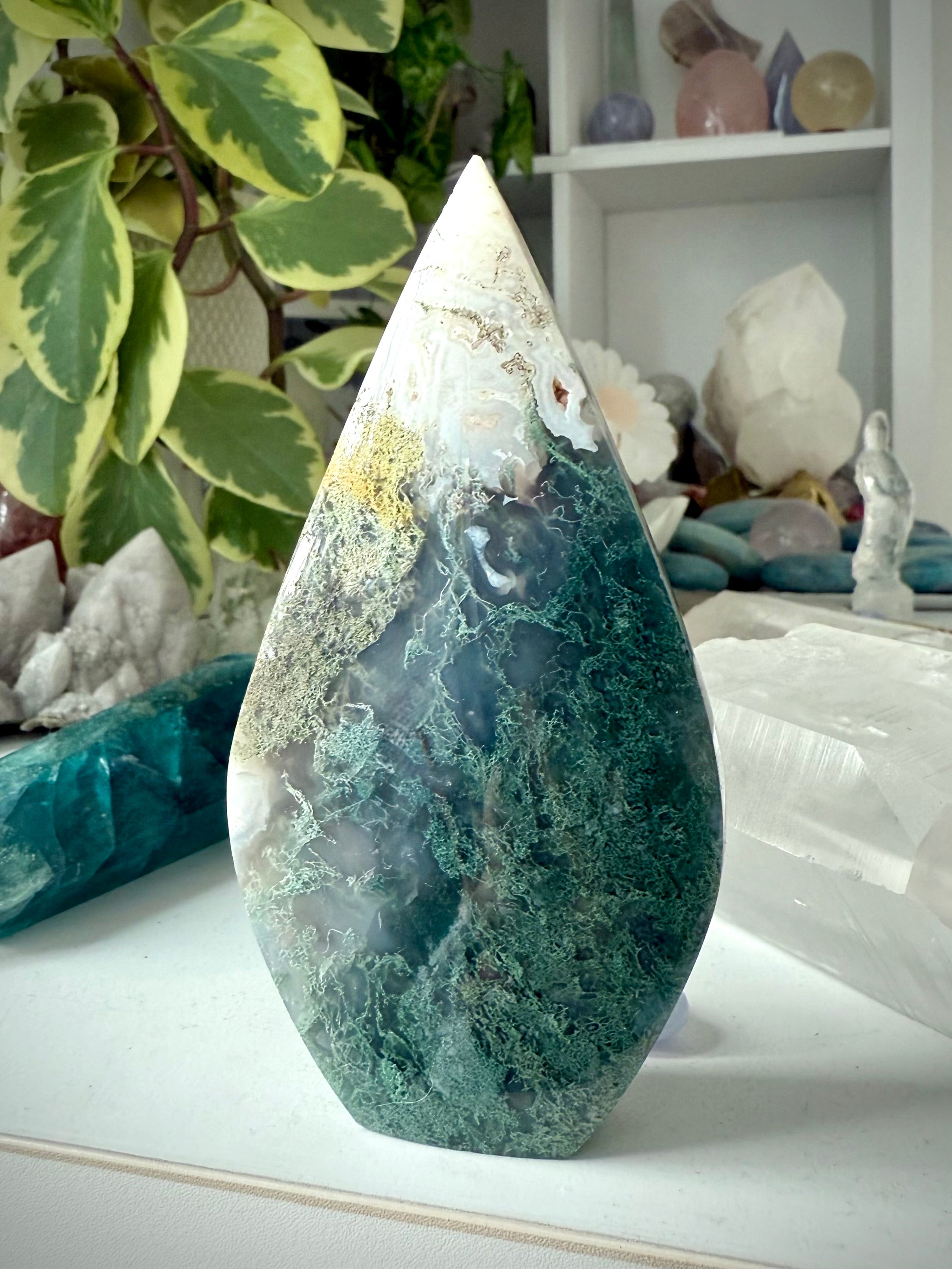 Moss Agate flame crystal displayed in sacred space with natural textures and earthy tones