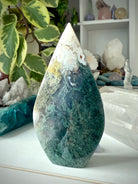 Moss Agate flame crystal displayed in sacred space with natural textures and earthy tones