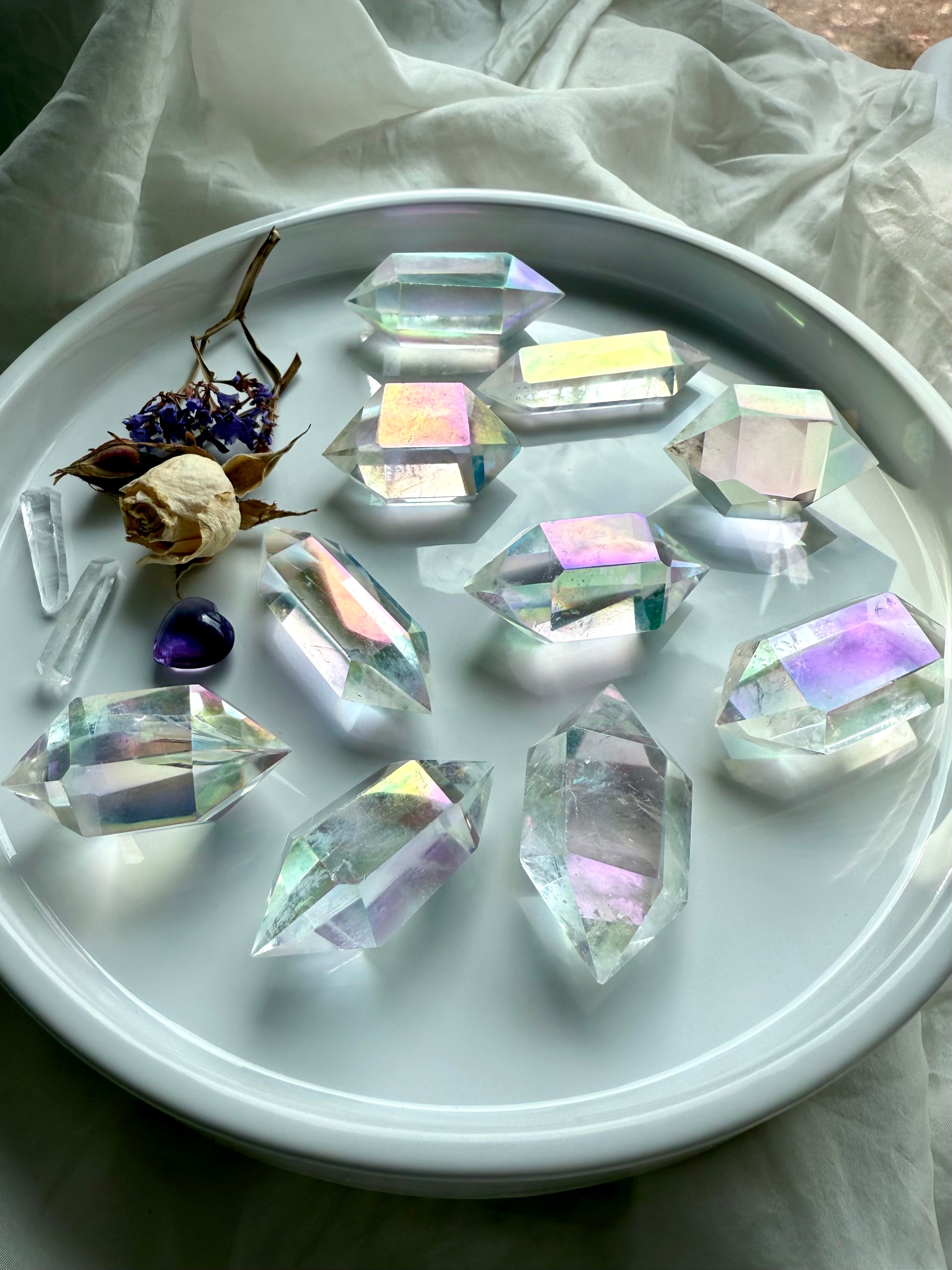 Collection of Angel Aura Quartz double terminated points arranged in a round dish with dried flowers and amethyst accent