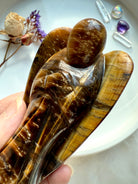 Close-up of polished Tiger’s Eye crystal angel showing detailed golden bands and natural shimmer 