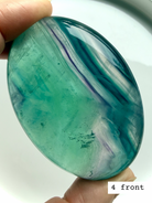 Teal fluorite palm stone #4 front view with vibrant blue green swirls and luminous glow in natural light