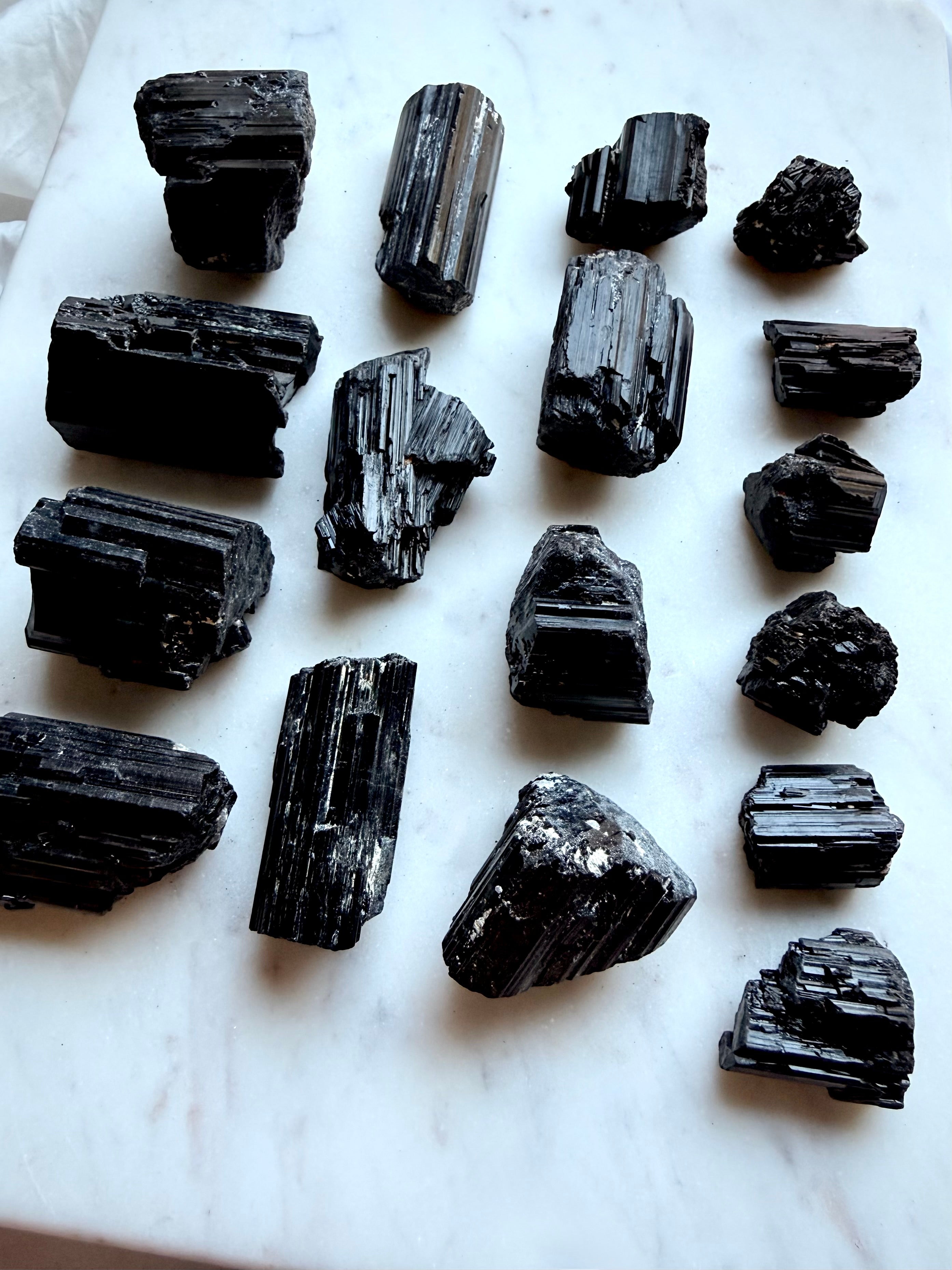 Raw Black Tourmaline chunks arranged by size showing varied natural shapes and crystalline formations