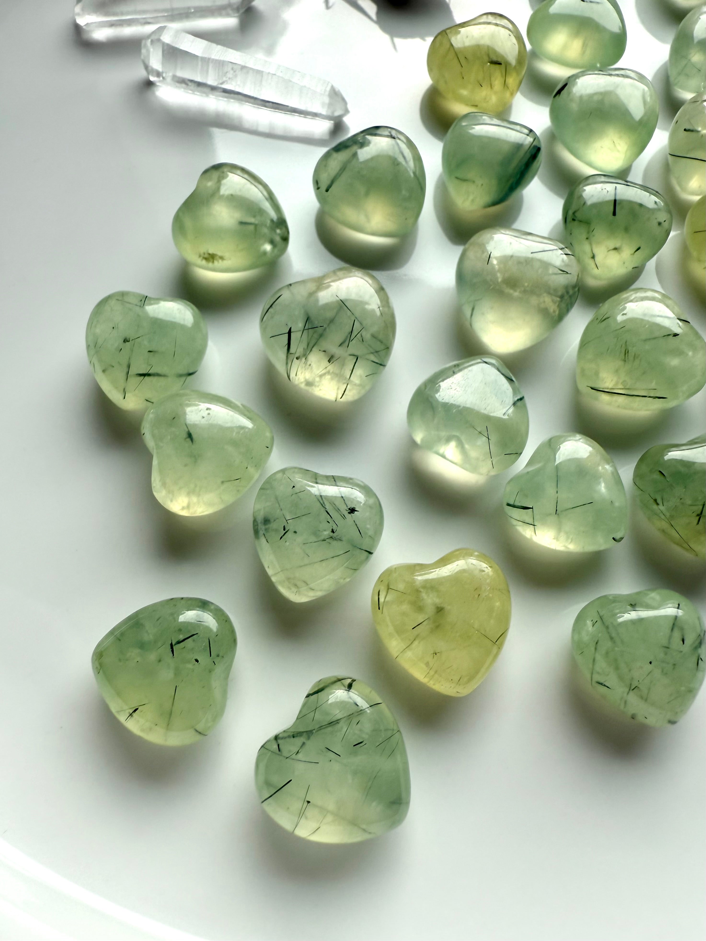 Mini Prehnite hearts with natural Epidote inclusions — polished pale green gemstone carvings for heart chakra healing and clarity.