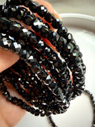 closeup of multiple faceted black spinel bracelets stacked together for grounding and protection