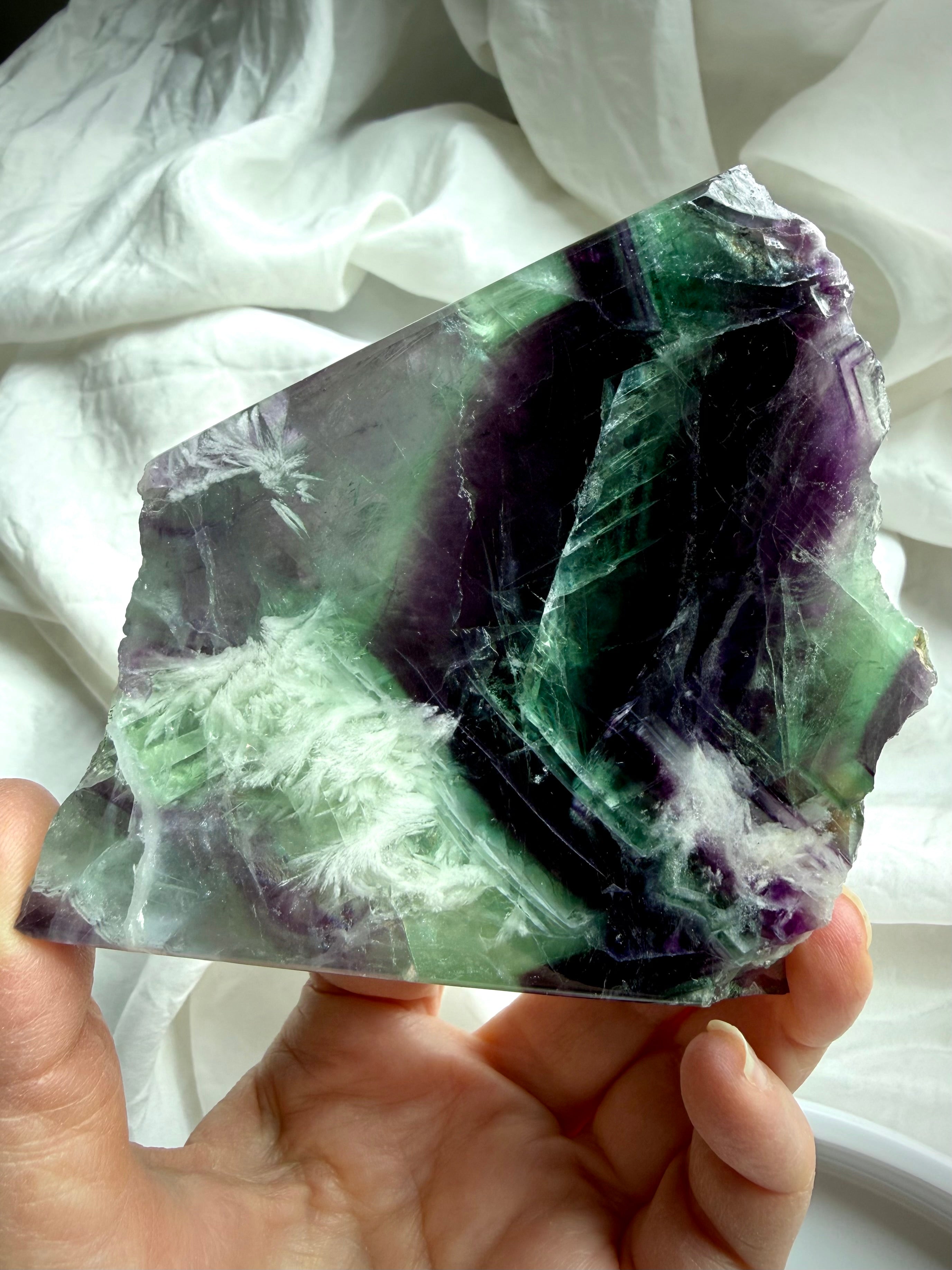 green and purple fluorite slab showing rainbow internal flashes and white scolecite snowflake inclusions