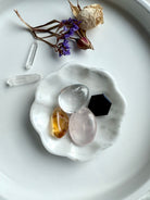 White marble daisy bowl styled with a mini crystal collection of rose quartz, clear quartz, citrine tumbles, with a black obsidian hexagon